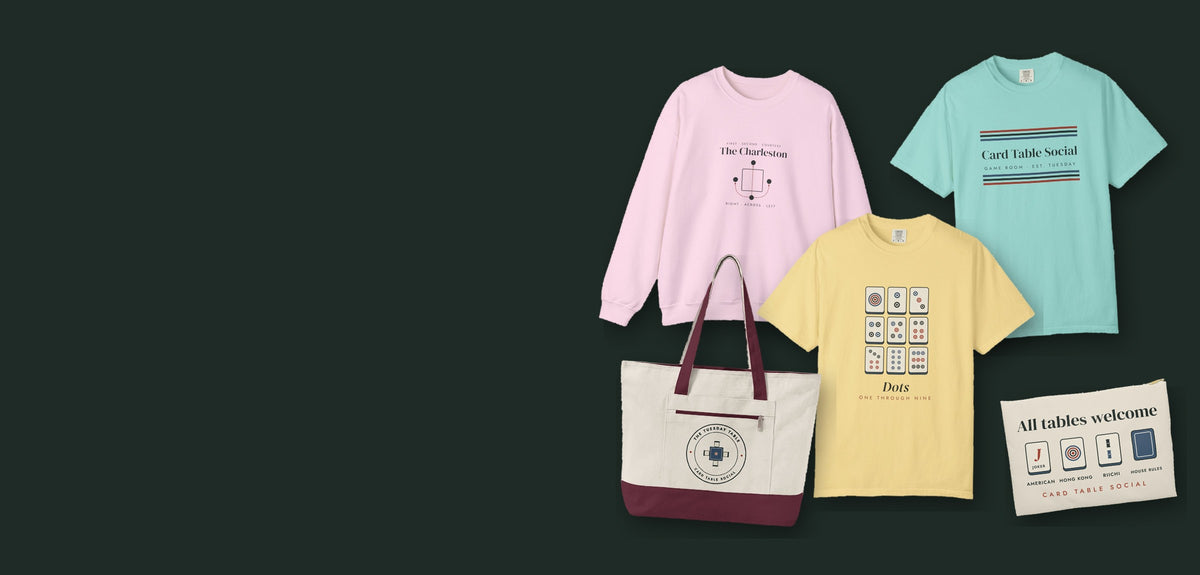 Card Table Social hero: The Charleston Crewneck in Light Pink, Game Room Stripe Tee in Chalky Mint, Dots Tee in Butter, The Tuesday Table Mahj Bag in Natural/Maroon and All Tables Welcome Zip Pouch in White zipper